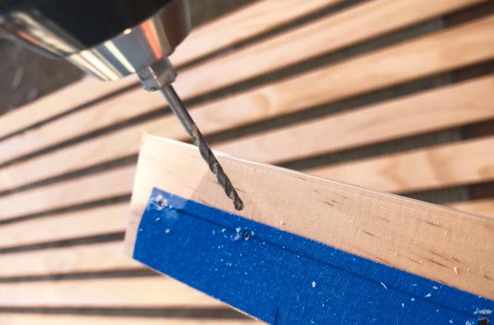 Close-up of timber with markings on masking tape and drill bit