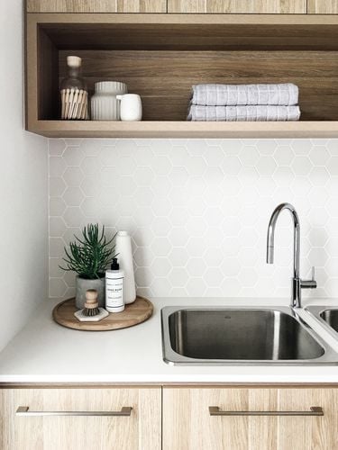 White kitchen benchtop with stainless steel sink and tapware and timber cabinets
