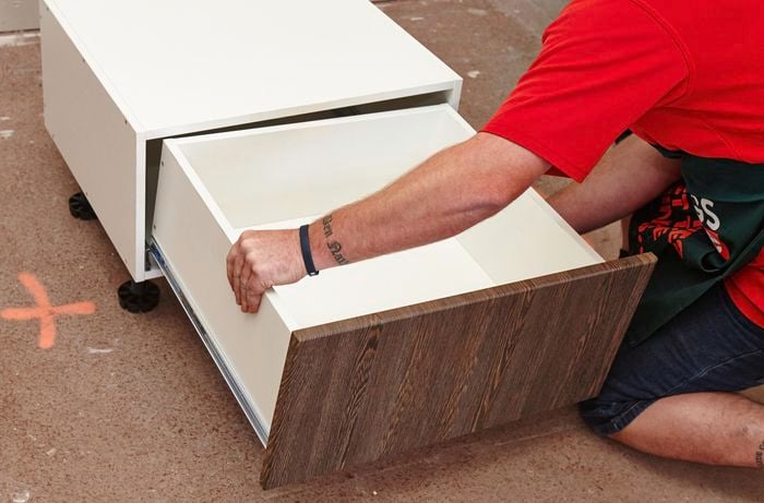 Person putting drawer into cabinet