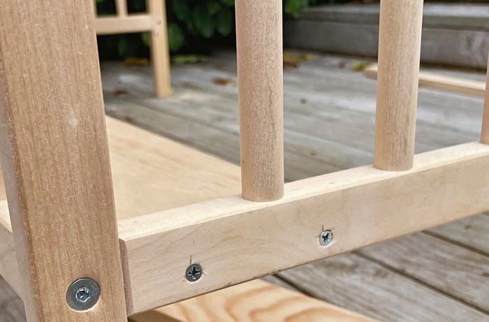 Wooden slat attached to bottom of frame and back supports with nails