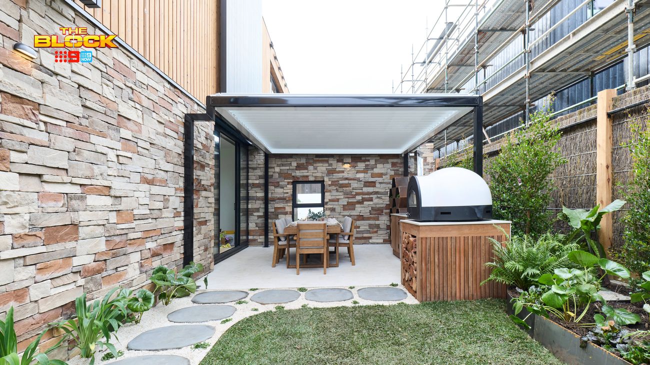 Modern outdoor courtyard featuring a covered dining area, stone feature walls, built-in pizza oven, stepping stones and landscaped garden beds.