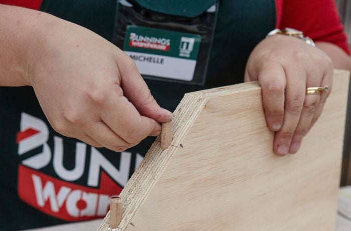 lengths of dowel fitted to a plank of wood onto which a similar piece can be mounted to make a corner shelf