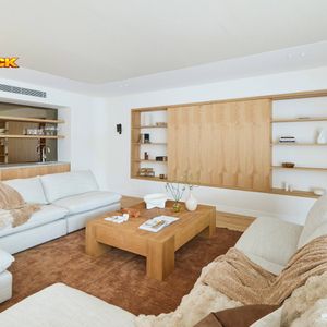 Contemporary living room featuring large neutral sofas, a timber coffee table and built-in timber shelving with concealed storage.