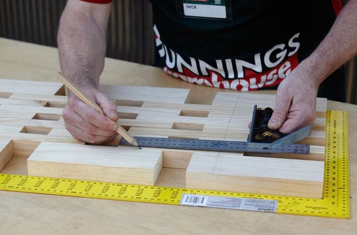 Person measuring timber frame with steel ruler.