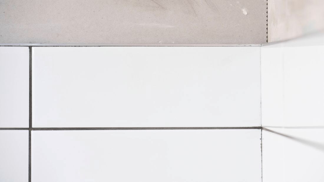 The image shows clean white wall tiles with tile trim and evenly spaced grout lines.