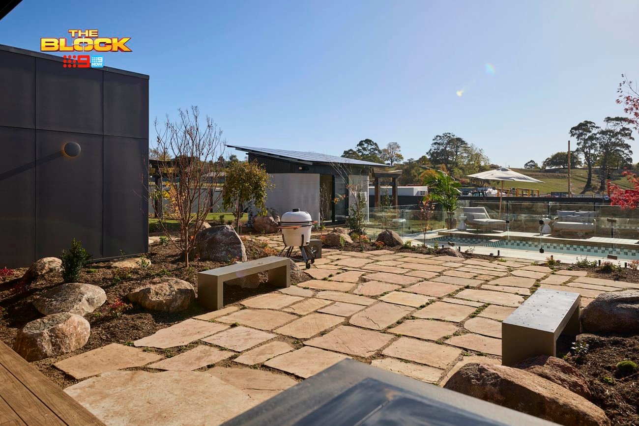The backyard with a paved area, a pool, an outdoor room and trees in it.