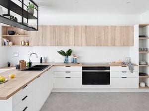 Kitchen with white and timber cabinets, a timber benchtop and floating shelves.