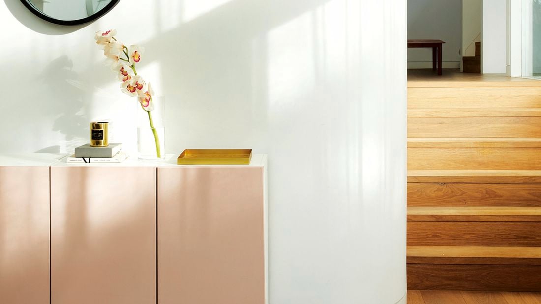 White buffet unit with dusty pink doors against a white wall