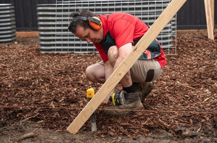 A Bunnings Team Member holding a power tool against a piece of timber