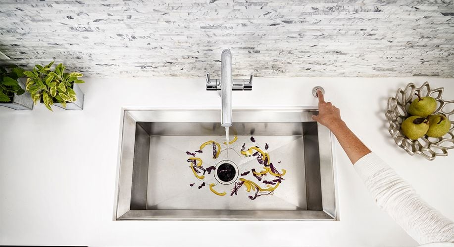 Person pressing InSinkErator button next to sink