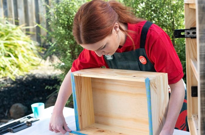 Woman applying tape around the edges of a drawer