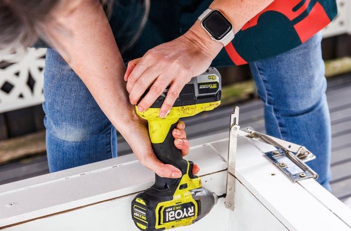 A person drilling the stays on the inside of the lid and the box.