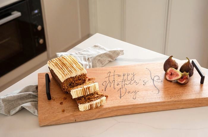 A piece of cake on a serving board with a happy Mother's Day design.