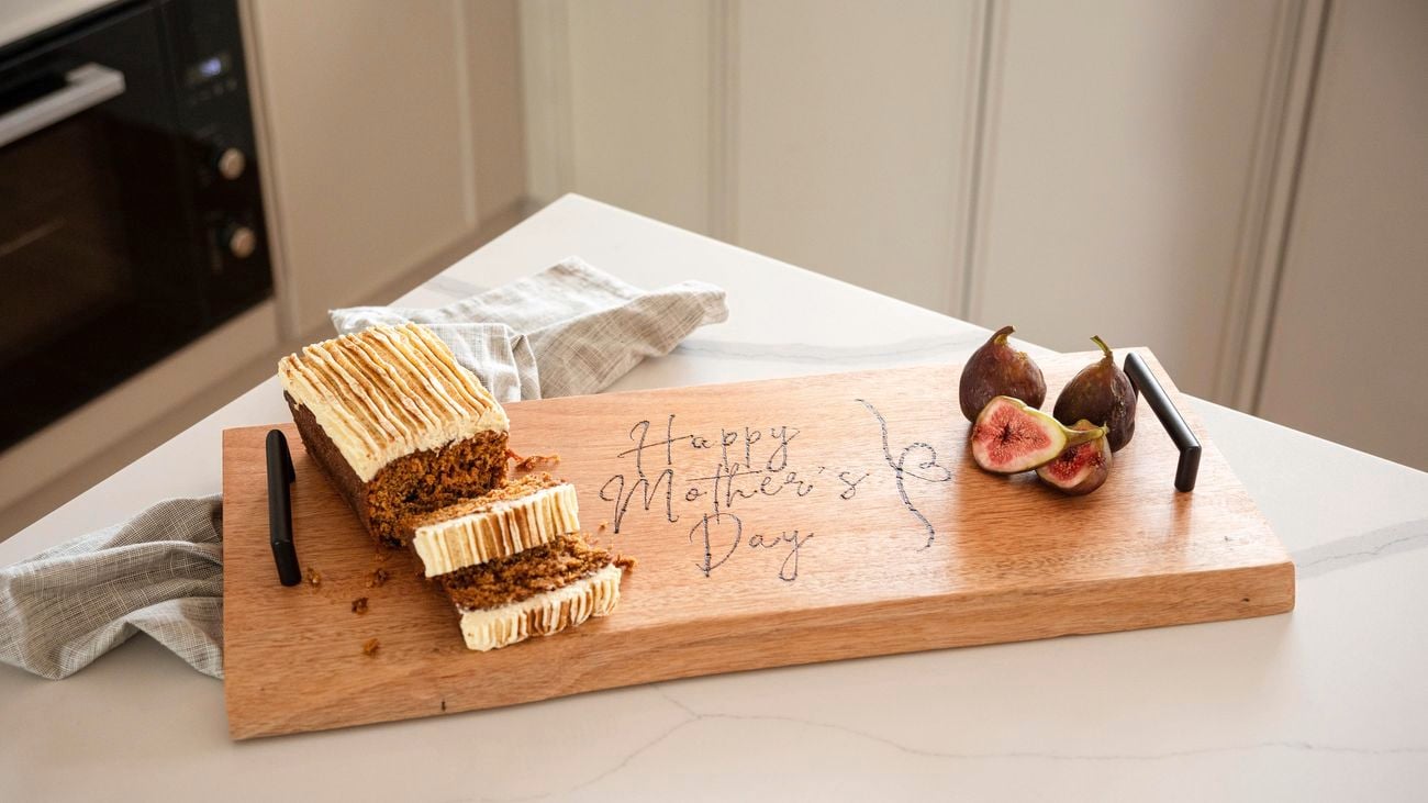 A piece of cake on a serving board with a happy Mother's Day design.