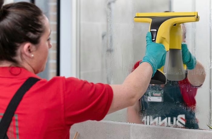 Person wiping a wet mirror with squeegee tool.