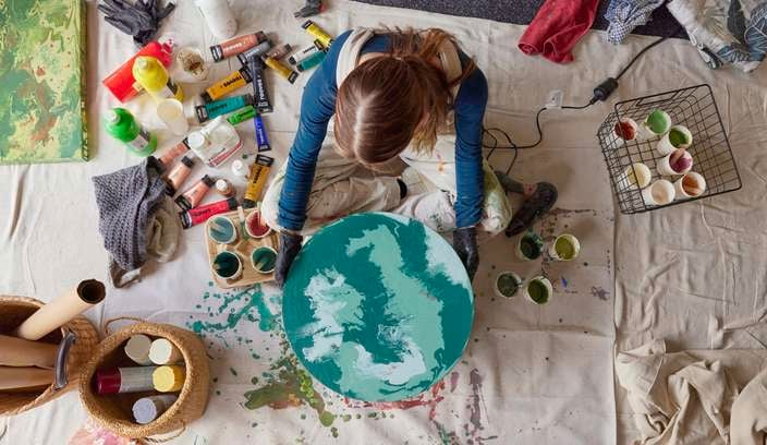 Bella in an art studio holding finished paint pour artwork