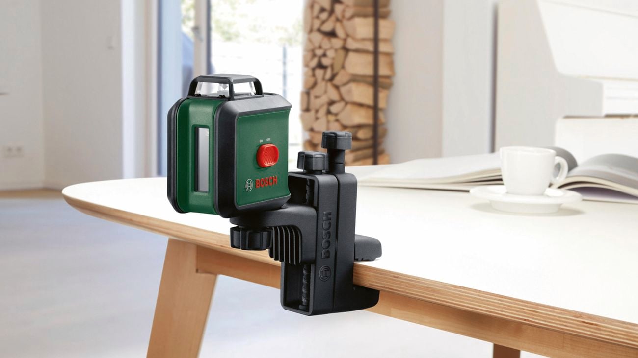 A man using a Bosch ‘Universal Level 360’ green beam line laser to measure fixtures