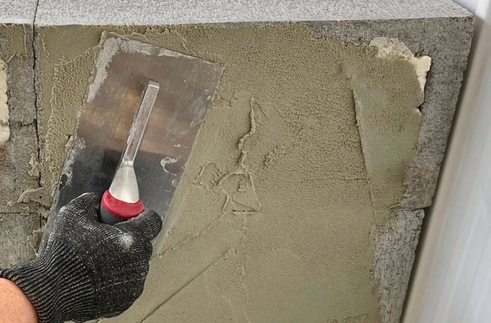 A person coating concrete blocks with render