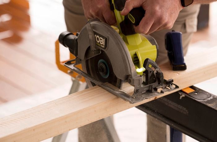 A person is using a circular saw to cut the base support timber.