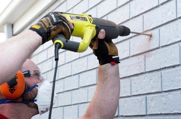 Person drilling hole into brick wall