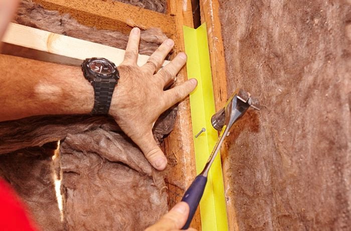 Internal angles being nailed into place on a bare wall