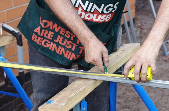 A person marking a length on metal frame