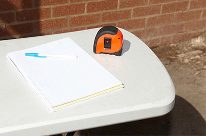 A pad and measuring tape on a table outside