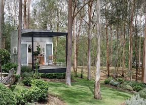 Small building clad in Colorbond with deck and French doors in a bushland garden