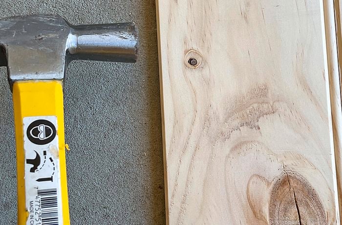 A person hammers the side of a pine panel