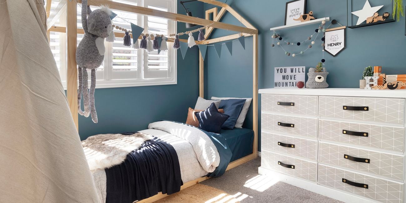 Kids bedroom with timber bed frame, bunting and toys.