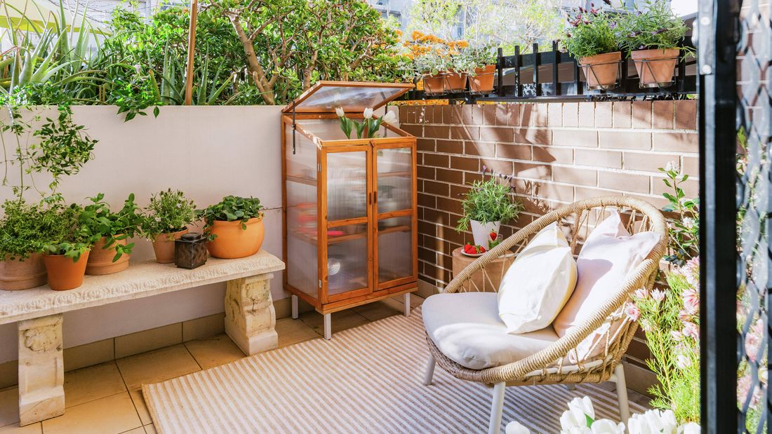 Apartment courtyard with raised garden beds, potted plants and a stone bench.