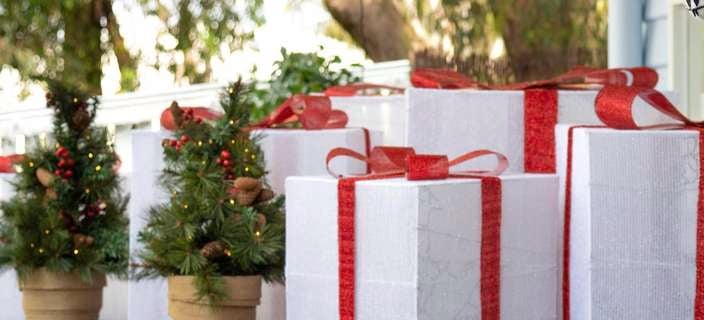 Front door styled with wreath, pots with small trees, rocking horse and wrapped gifts.