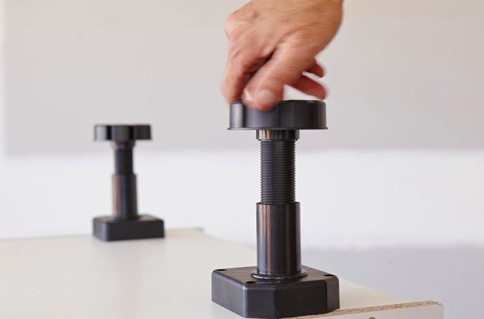 Plastic feet being adjusted on an oven cabinet