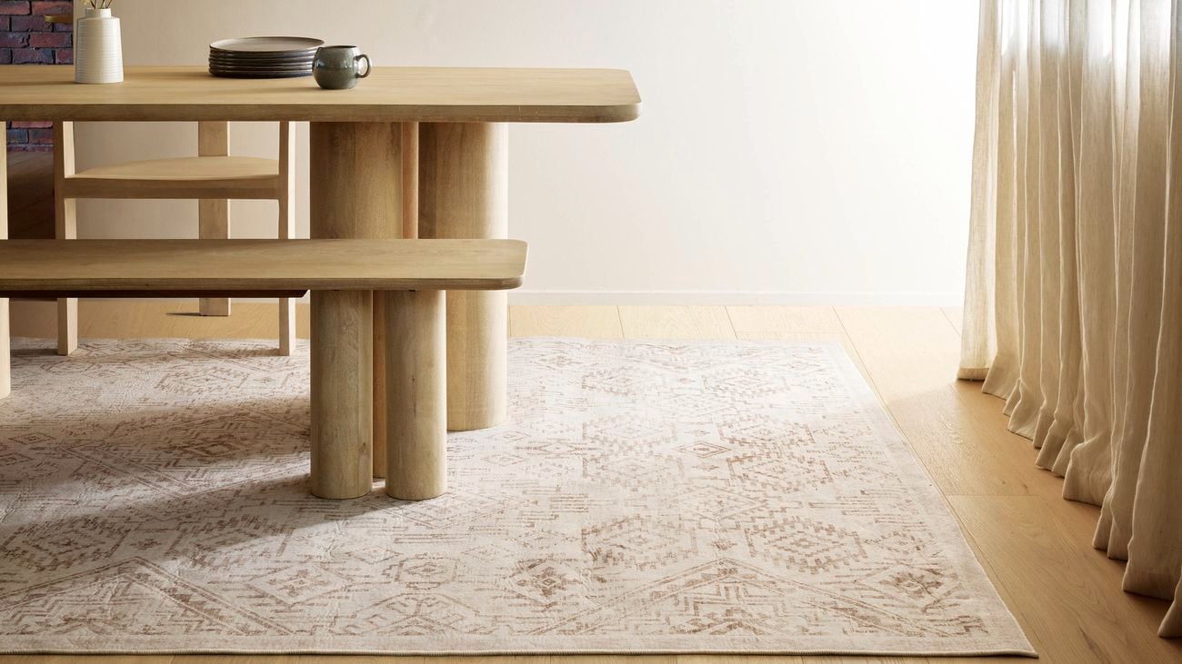 Light timber flooring with timber dining table sitting on soft browns/cream rug