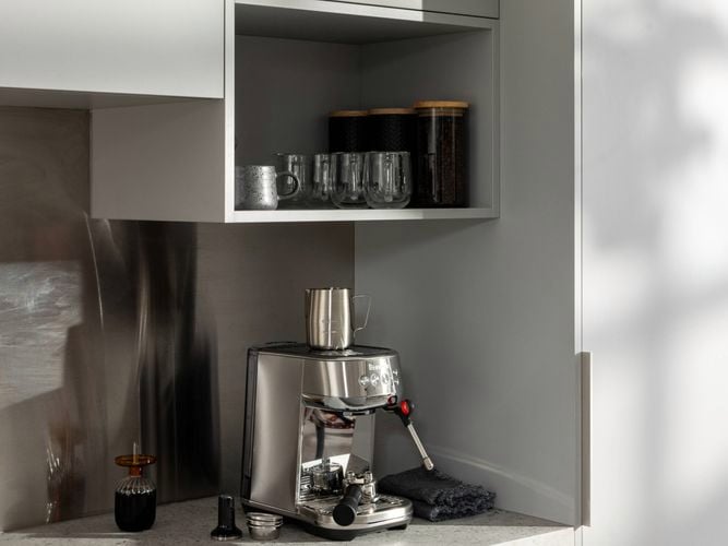 Kitchen with grey cupboards, marble benchtop with a coffee machine on it.