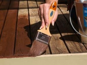 Close-up of someone using a Monarch paintbrush to apply deck sealant