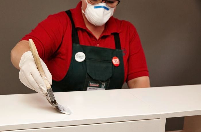 An assembled kids storage bench being painted white by a Bunnings team member