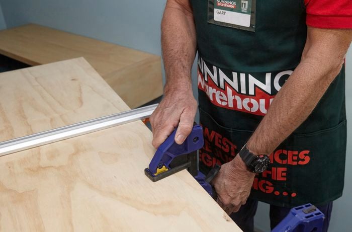 A person fixing a clamp to a timber panel