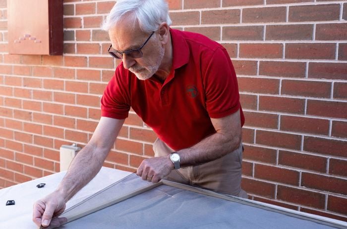 A Bunnings Team Member is carefully removing the mesh screen from the frame. 