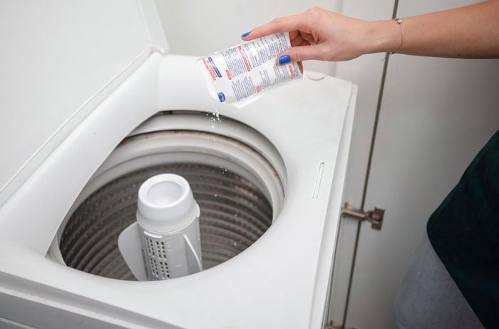 Pouring cleaner sachet inside the washing machine. 