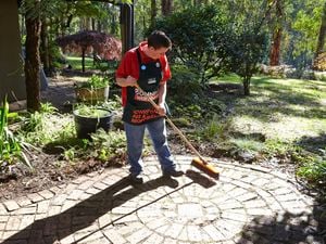 Bunnings team member sweeping bricks in a garden