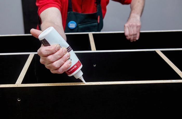 Person applying PVA glue to cabinet