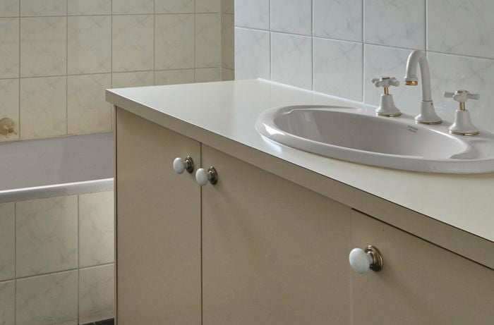 Dated bathroom tiles in cream and yellow colours.