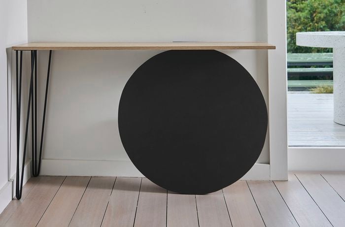  A close up of the black circular feature and hidden shelf of a hallway entrance table.