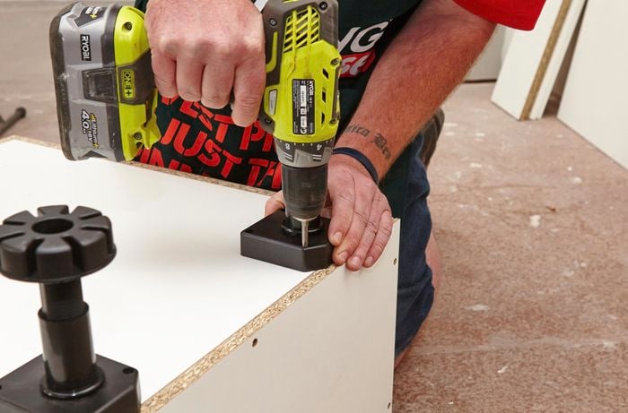 Person screwing legs into base of cabinet