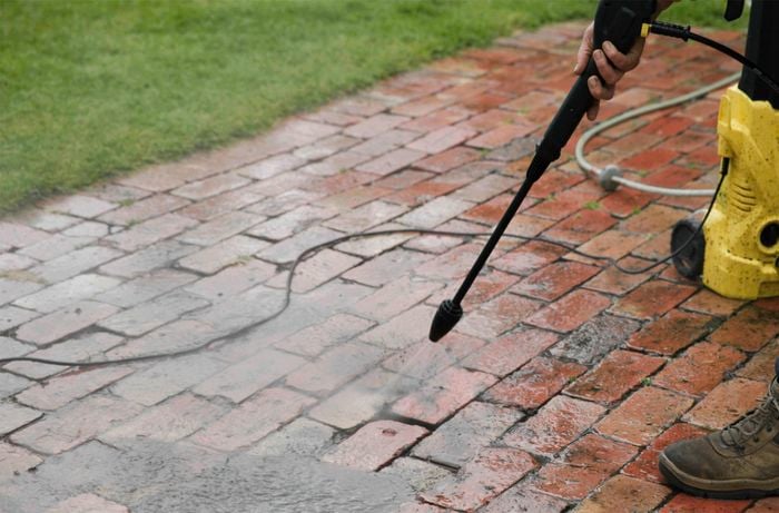 A person pressure washing a old brickwork.