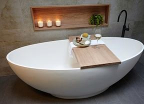 A free-standing bath with a timber shelf holding food and a glass of wine