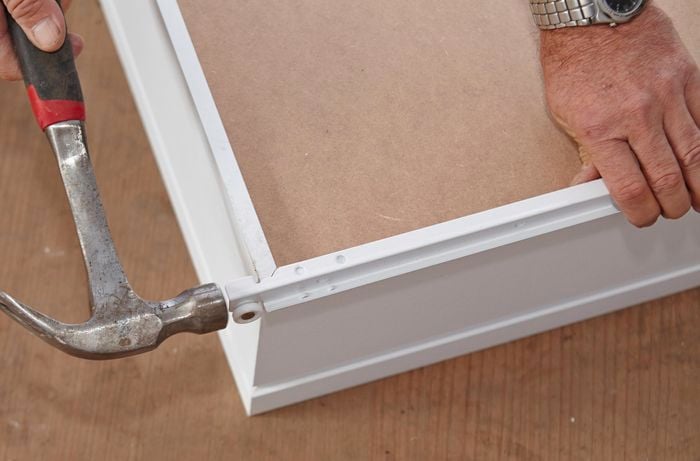 Person attaching drawer runner to wardrobe drawer.