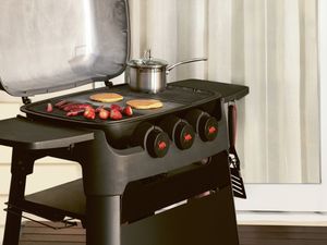 Black barbecue with strawberries and pancakes cooking on a wooden deck