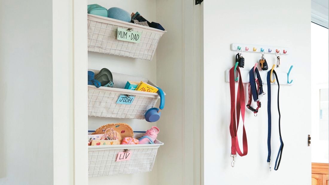Hall closet with door open showing wall-mounted wire baskets for storage and hook racks holding dog leads and keys for a hall closet makeover